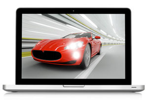 Laptop, screen shows image of red sports car racing down road